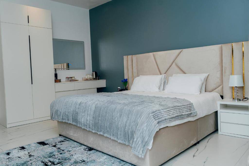 a bedroom with a large bed with a blue wall at The Gardens in Marracuene