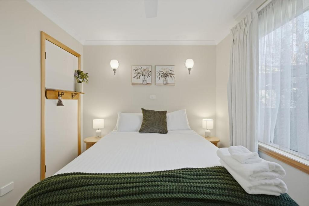 a bedroom with a large white bed with towels on it at Sunlit Garden Granny Flat in Devonport