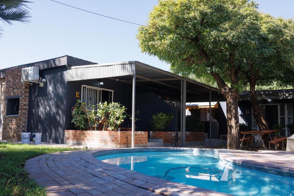 a swimming pool in front of a house at Cosy Cottages Guesthouse in Potchefstroom