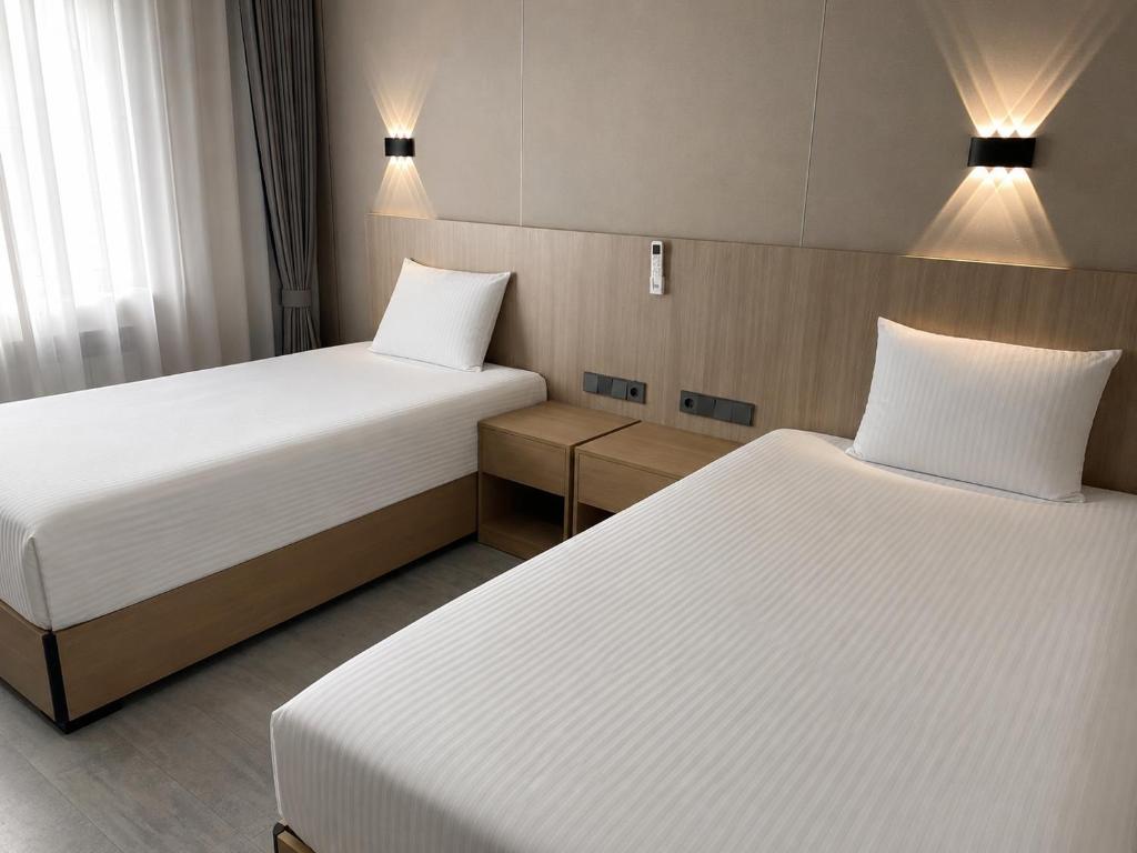 a hotel room with two beds and two lamps at AiRom Hotel in Atyrau
