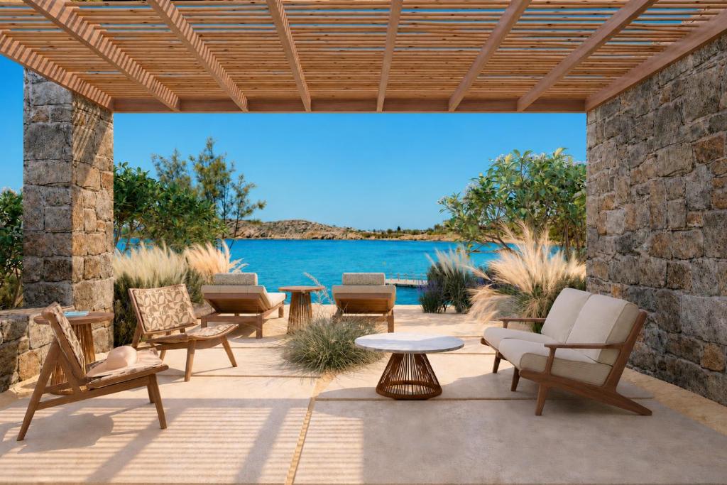 a patio with chairs and a table and water at Fouquet's Mykonos in Mikonos