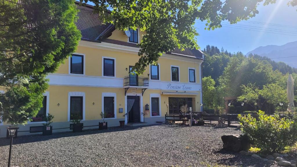 a large yellow building with a balcony on it at Pension Leano in Nötsch
