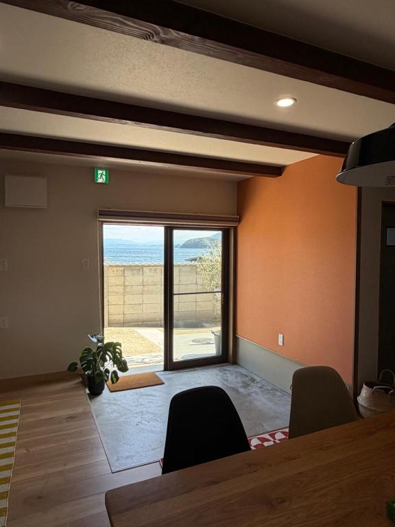a dining room with a table and chairs and a large window at 海辺の宿なみとけ in Shodoshima