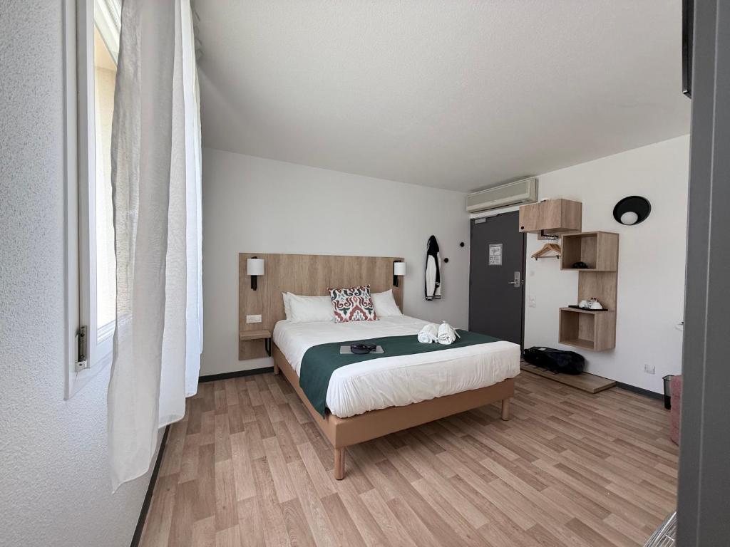 a bedroom with a large bed in a room at Hotel Atena Bordeaux Sud Est - Vélo Friendly in Créon