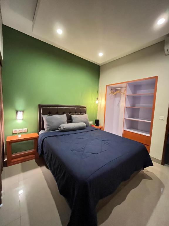 a bedroom with a blue bed with a green wall at Kalih Homestay Bali in Kuta