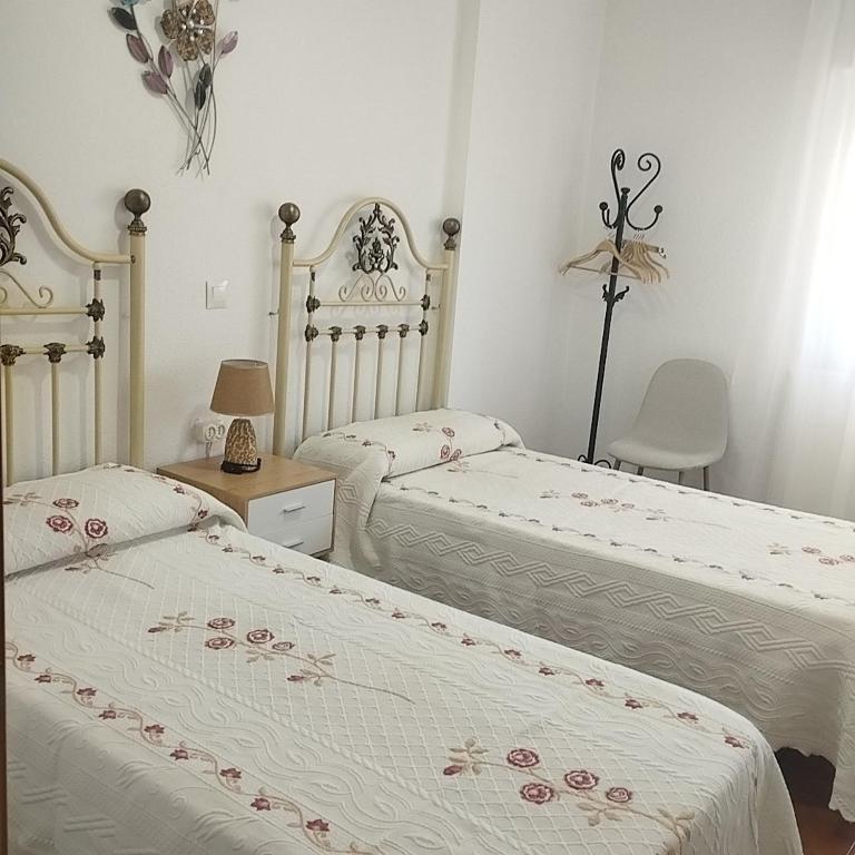 a bedroom with two beds and a table with a chair at Casas los Rosales in Guadix