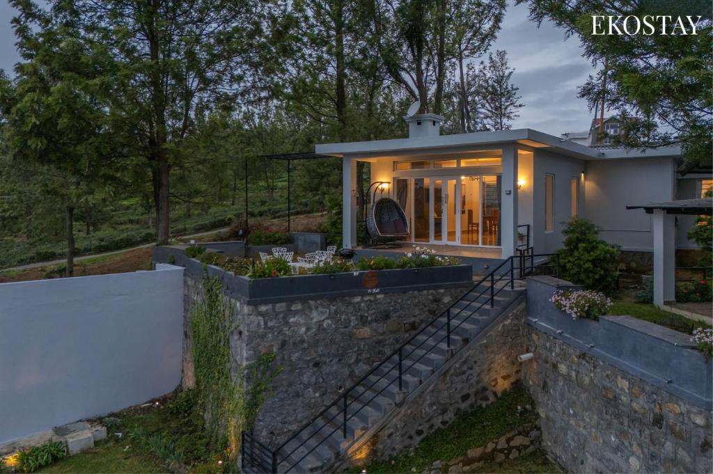 a home with a stone retaining wall and a house at EKOSTAY - Skyfall Mist Villa in Ooty