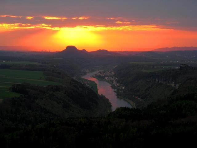 a view of a river at sunset with the sun setting at Pension Fuhrmann's Elb- Café in Bad Schandau