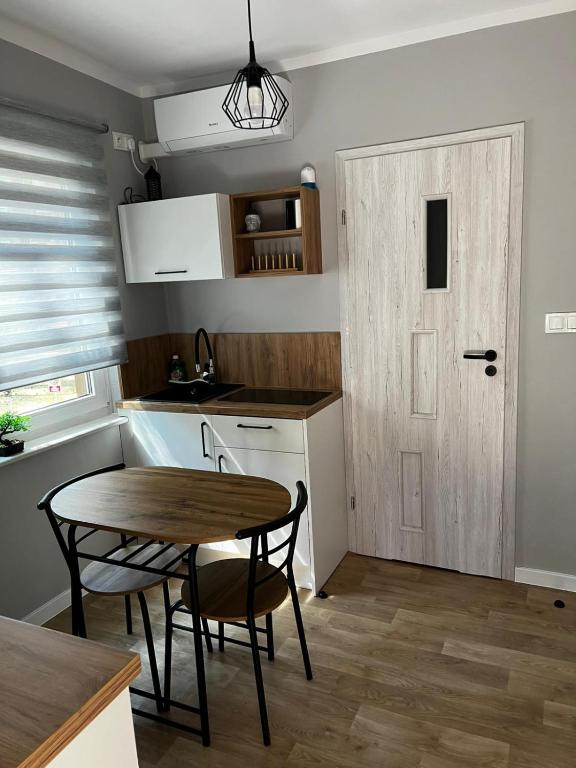 a small kitchen with a table and a door at W sosnowym lesie 2 in Lubniewice