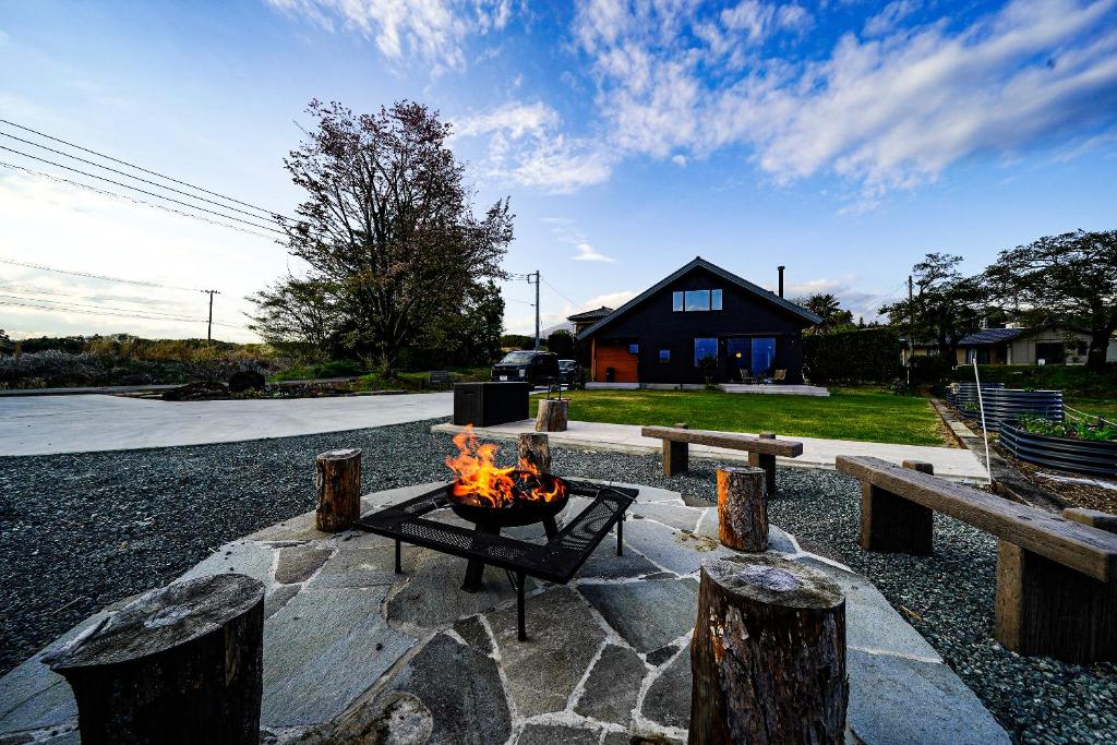 a fire pit in a yard with benches and a house at Nodokaan Yatsugatake Private Villa in Hokuto