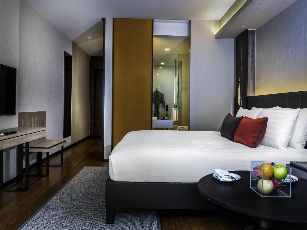 A contemporary bedroom with a round table, fruit plate and visible shower area.