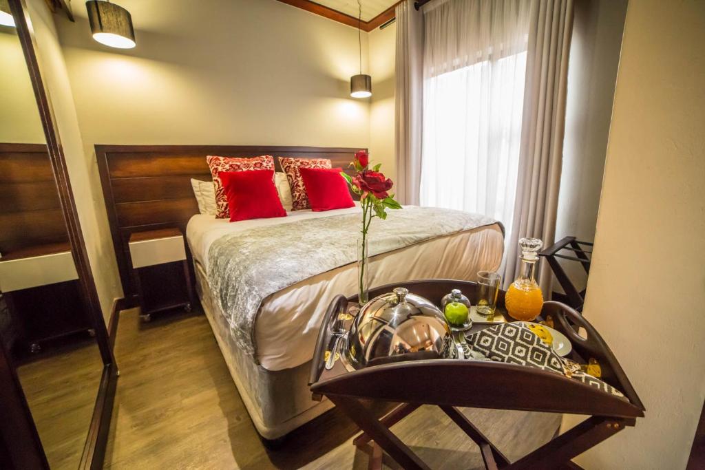 a bedroom with a bed with red pillows and a table at Grey Manor Guesthouse in Potchefstroom