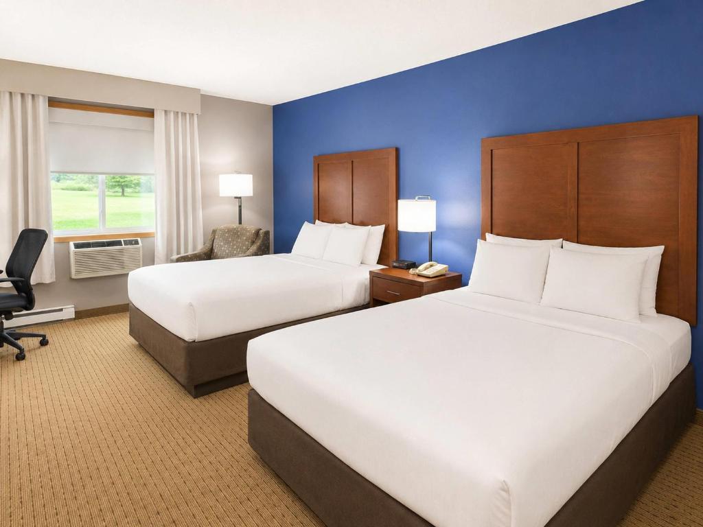 a hotel room with two beds and a chair at Comfort Inn Iron Mountain North in Iron Mountain