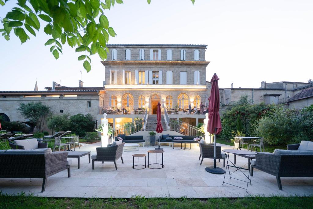a patio with chairs and tables in front of a building at Pavillon des Millésimes in Lussac