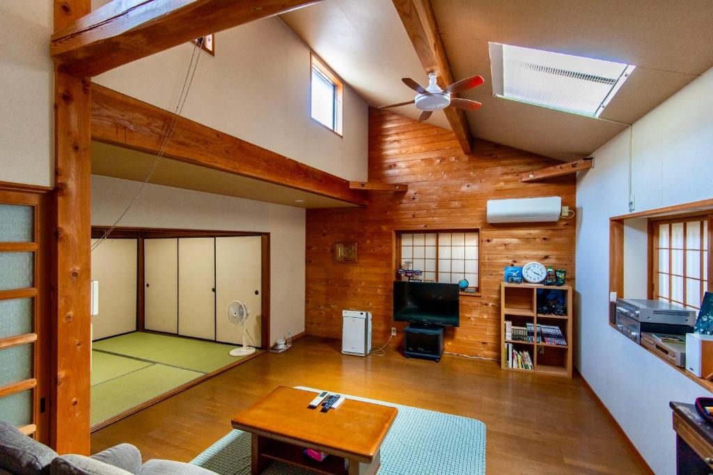 a living room with a ceiling fan and a room with a table at 古民家一棟貸 鴨部巣 kamobese in Kochi