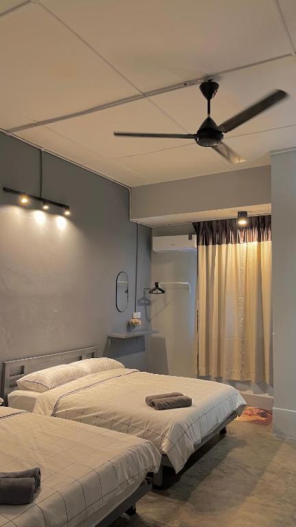two beds in a room with a ceiling fan at Roomah Ipoh En-suite attached-Bath R2 in Ipoh
