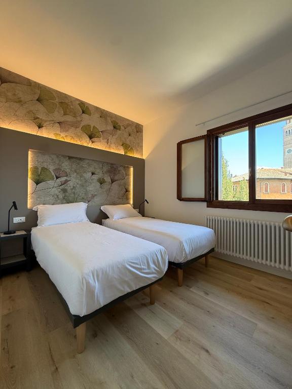two beds in a room with a stone wall at LEON D'ORO - Art Hotel in Pieve di Soligo