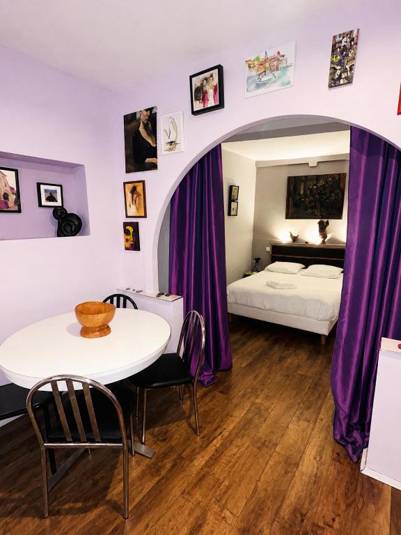 a bedroom with a table and a bed and purple curtains at Lumière de Collioure in Collioure