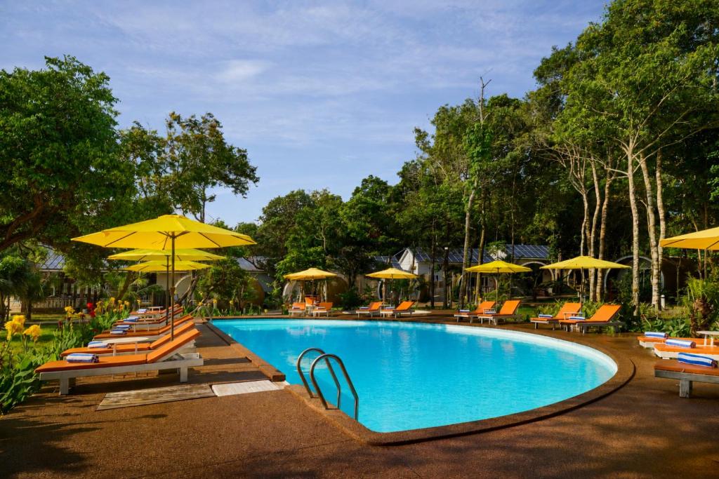 a swimming pool with chairs and umbrellas at Sandy Beach Bungalows by EHM in Koh Rong Sanloem