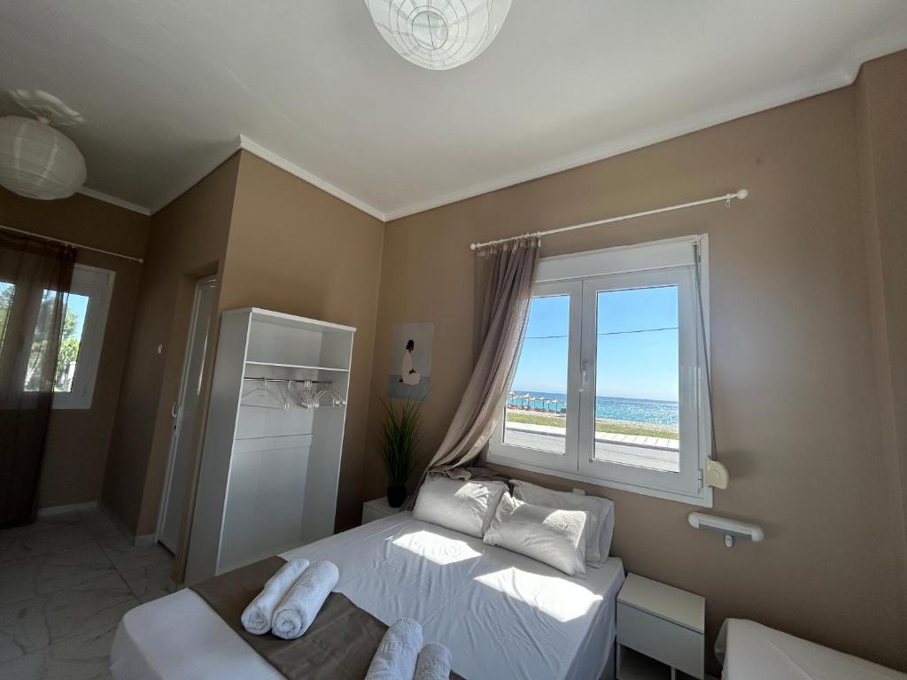 a bedroom with a bed and a window with the beach at Basilio's Studios in Leptokarya