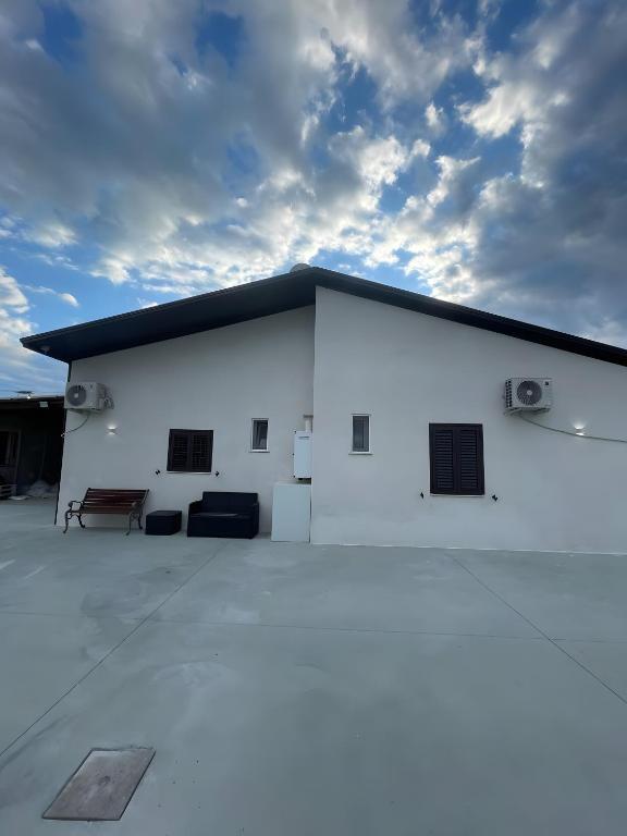 a white building with a bench in front of it at Affittacamere Sisca Oriolo in Schiavonea