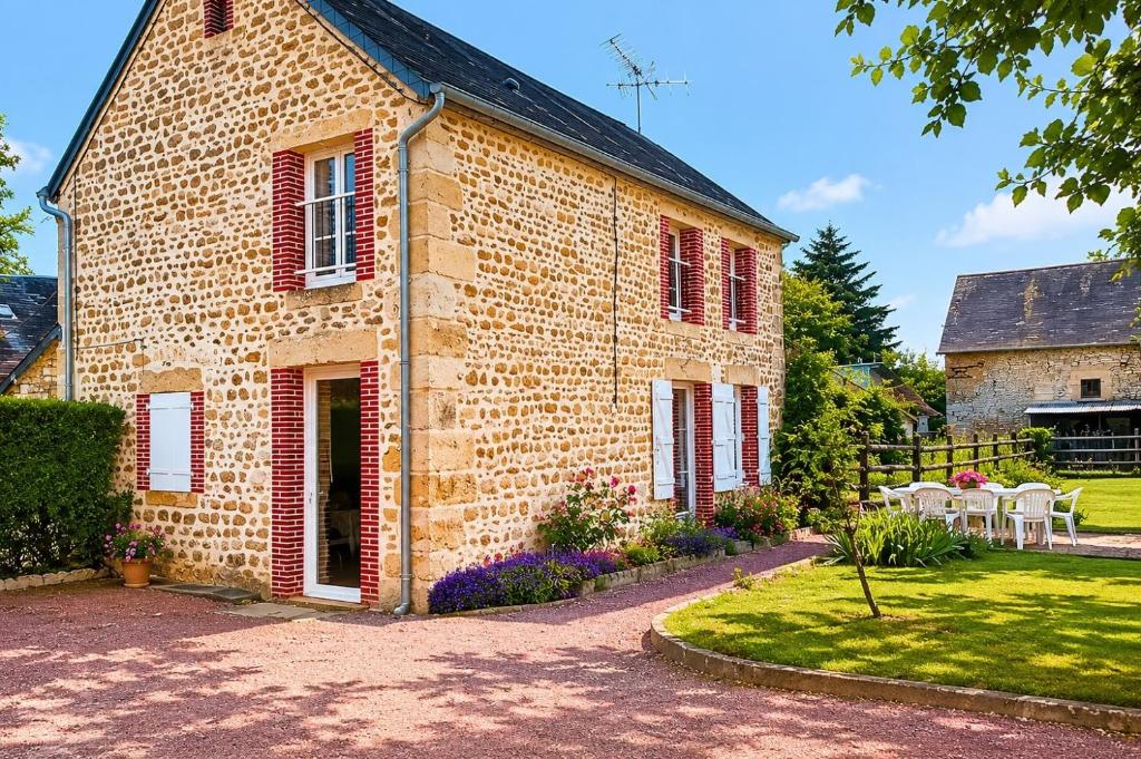 a brick house with red windows and a yard at La Maison des Filles in Sainte-Scolasse-sur-Sarthe
