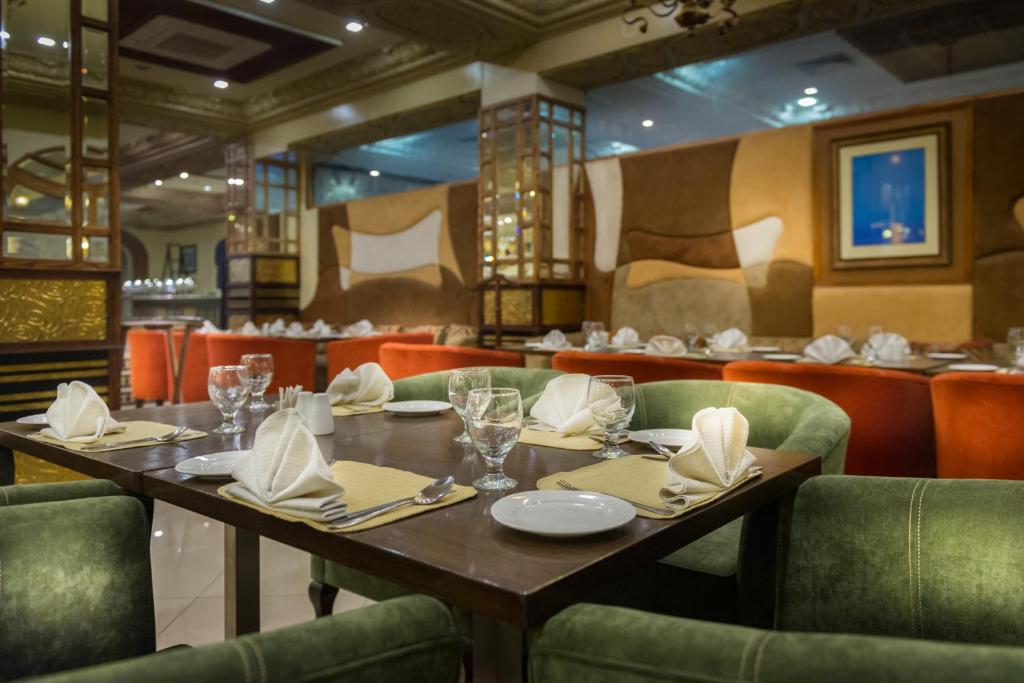 a restaurant with a wooden table and green chairs at Luxus Grand Hotel in Lahore