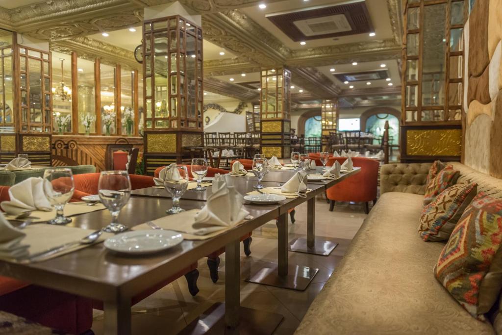 a dining room with tables and chairs in a restaurant at Luxus Grand Hotel in Lahore