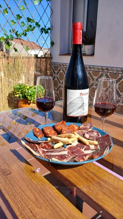 a bottle of wine and a plate of food and wine glasses at El Molinero in Monesterio