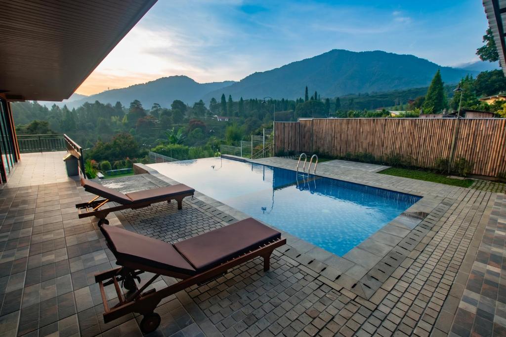 a swimming pool with a table and chairs and mountains at Villa Favore in Puncak