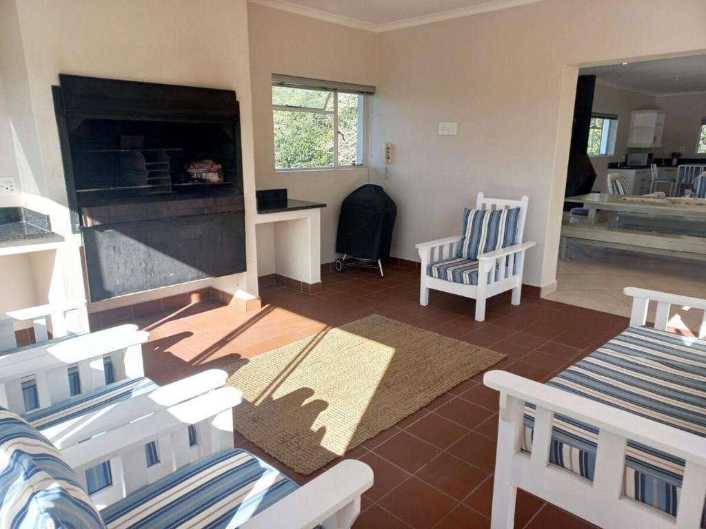 a living room with two chairs and a fireplace at Ripples Beach House - 14 sleeper in Port Alfred