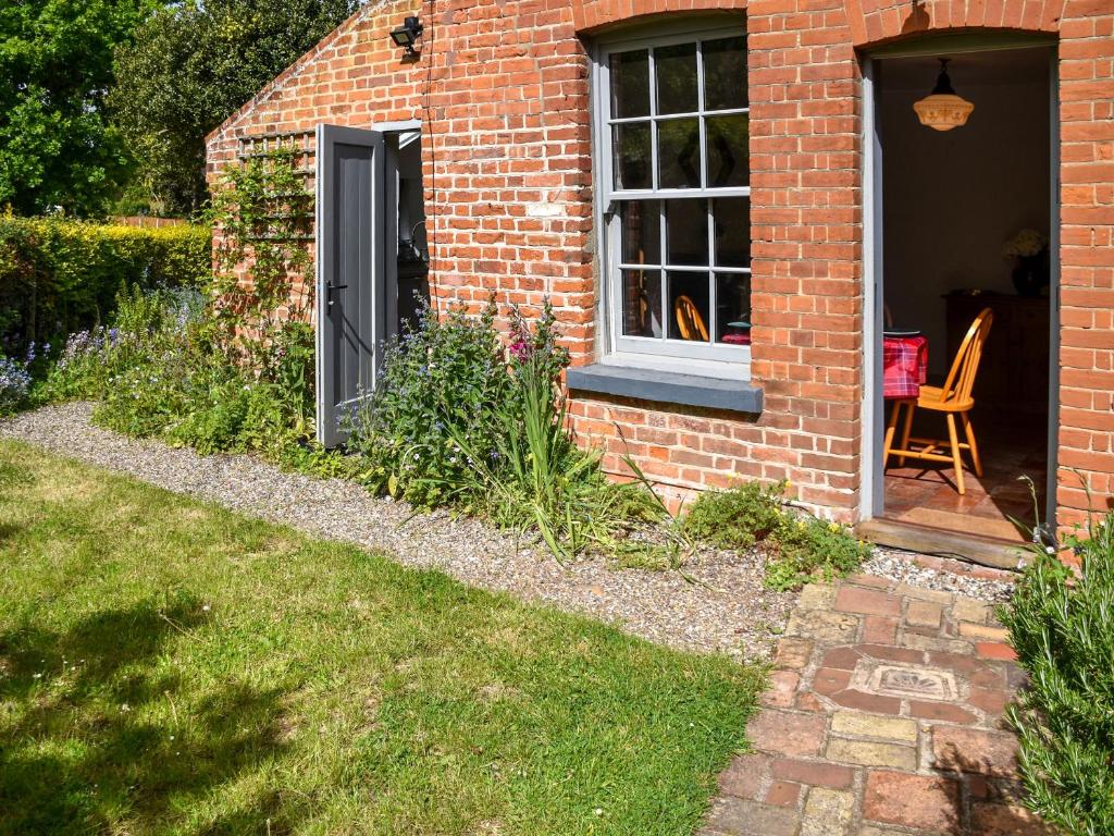a brick house with a window and a chair in a yard at Mark's Cottage in North Walsham