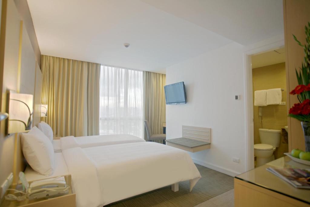 a hotel room with a white bed and a television at St Giles Hotel Makati in Manila