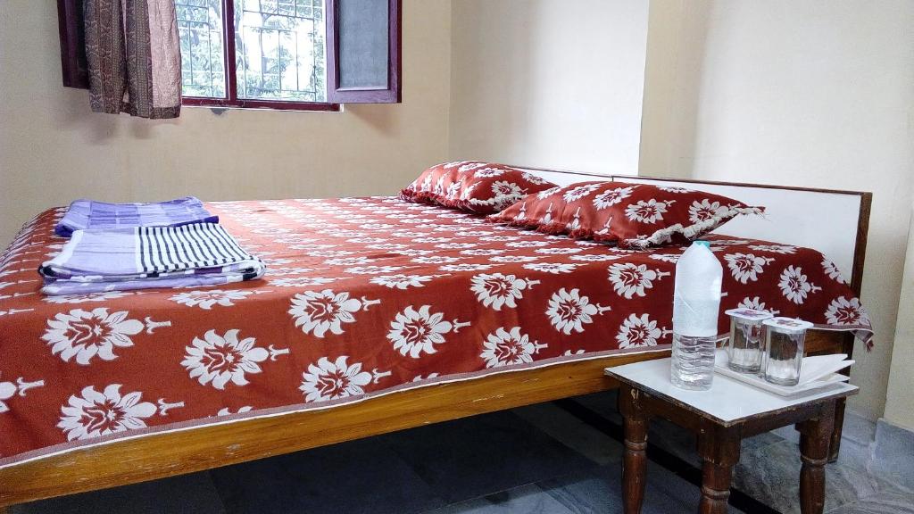 a bed with a red and white blanket and a table at Laxmi Lodge in Rishīkesh