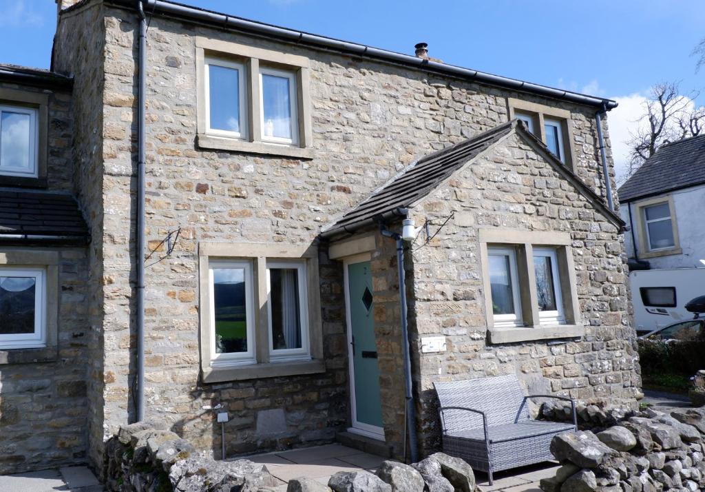a stone house with a bench in front of it at 2 Rock View in Settle