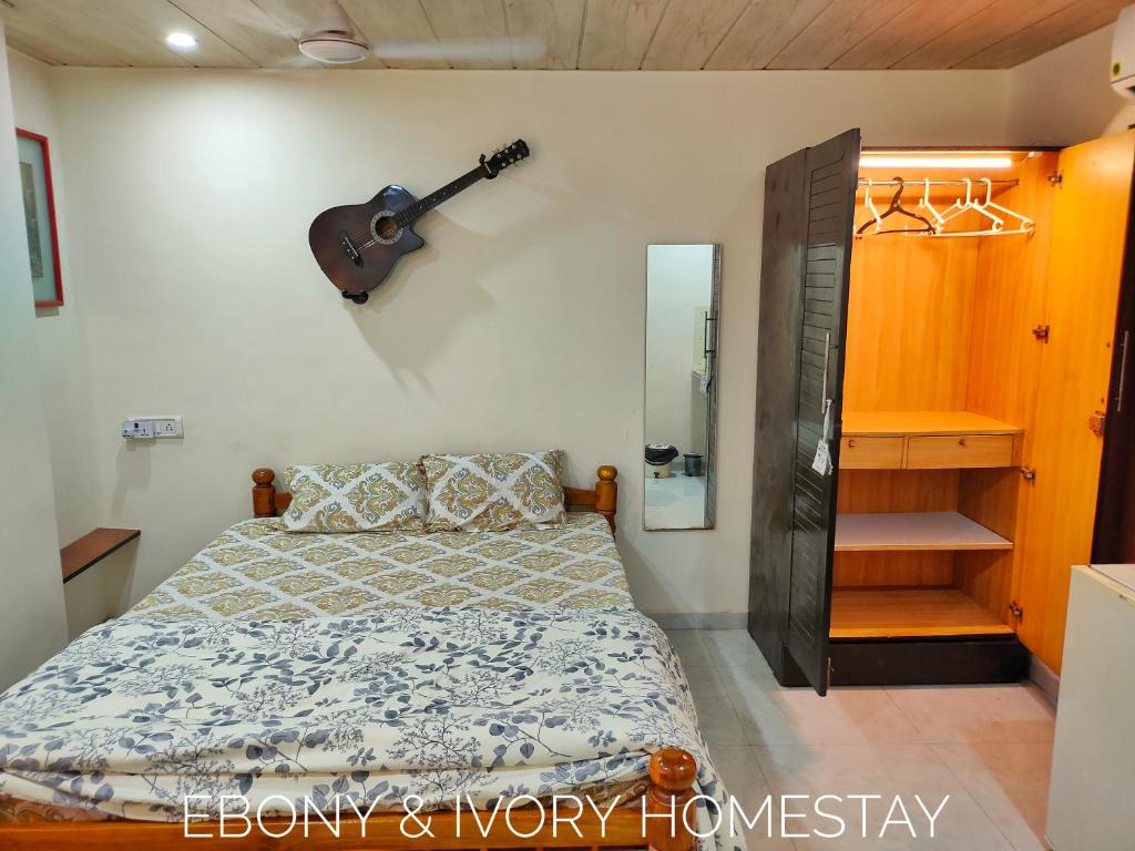 a bedroom with a bed and a guitar on the wall at Ebony Room - AC, Kitchenette, Ensuite, Independent Homestay in Mumbai