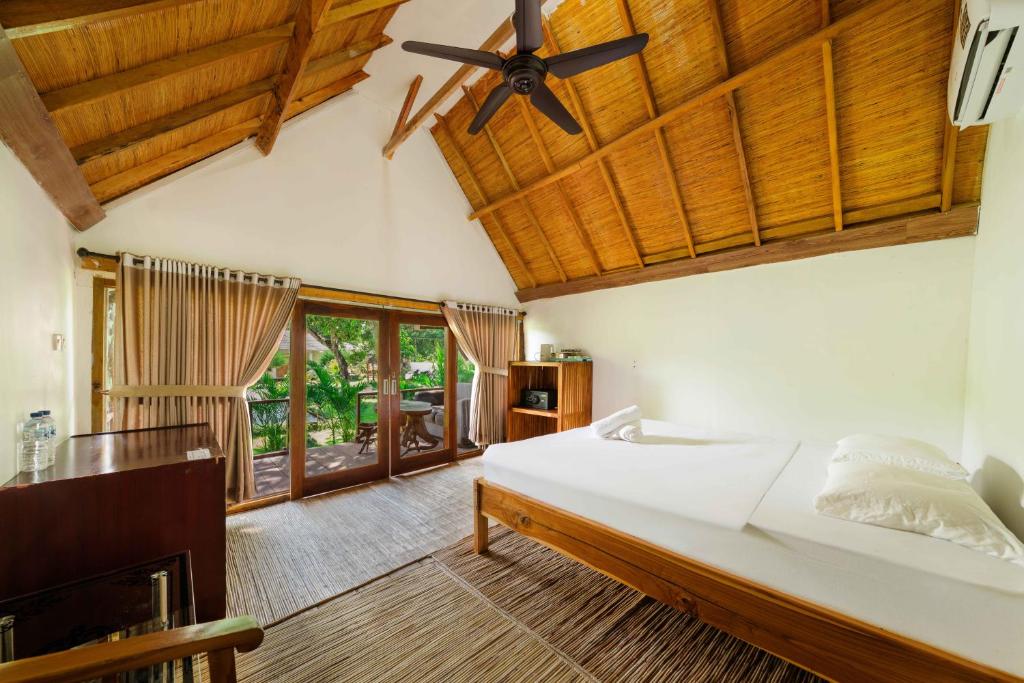 a bedroom with a bed and a ceiling fan at Kaia Raya Surf Lodge in Maluk