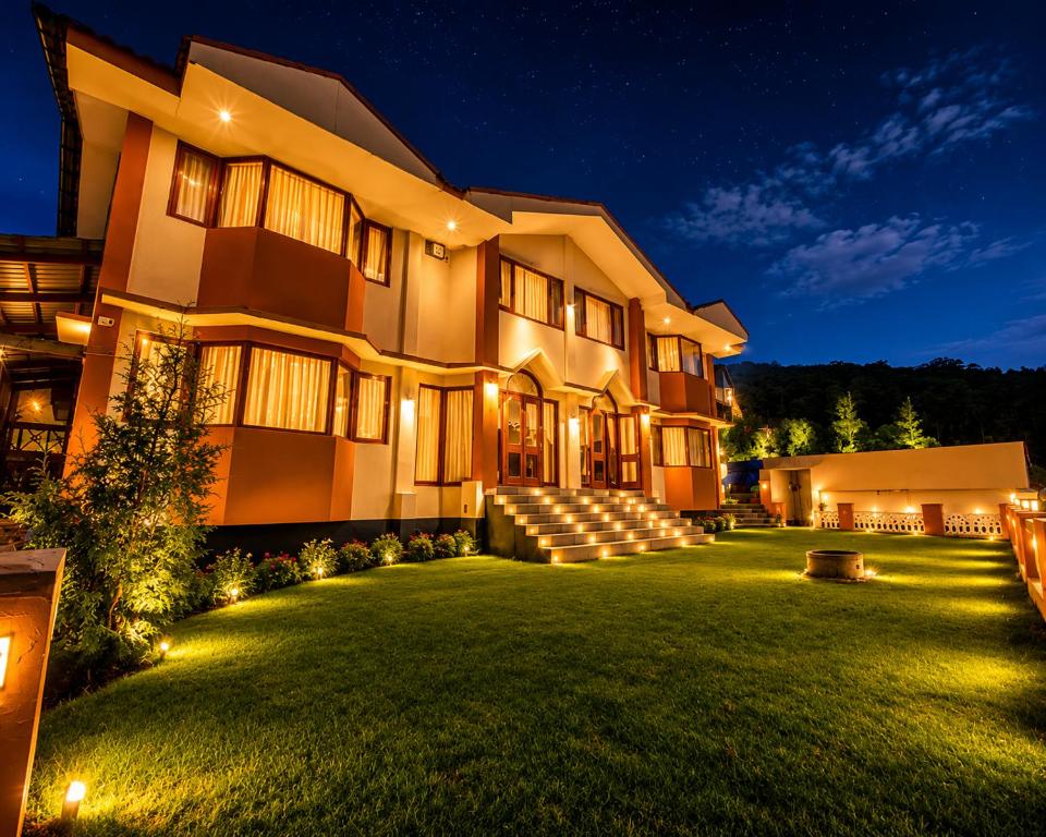 a large building with a green yard at night at Winterfeel Bellmount by Neon Nest in Ooty