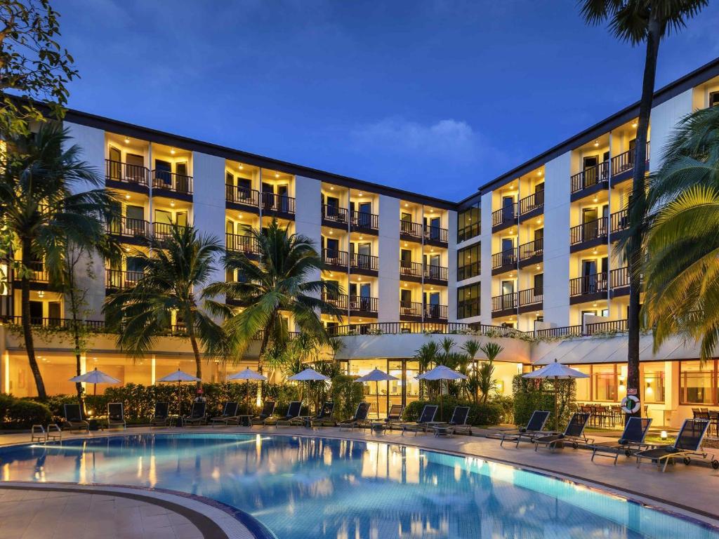a hotel with a swimming pool in front of a building at Ibis Phuket Patong in Patong Beach