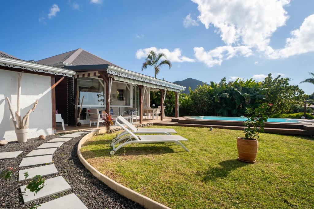 a backyard with a white chair and a pool at Villa Le Nid des Colibris in Gourbeyre