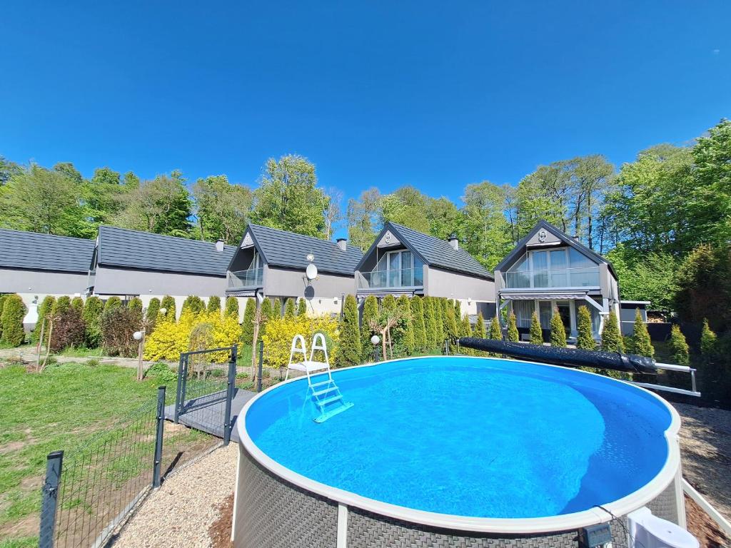 a house with a swimming pool in the yard at Sowi Kąt - Domki z Baliami oraz Tradycyjne in Lubiatowo