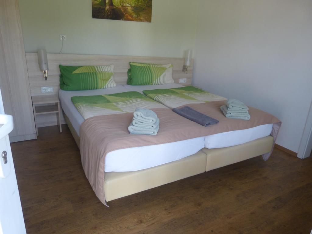 a large bed with green pillows and towels on it at Pension Zur Eiche in Drebenstedt