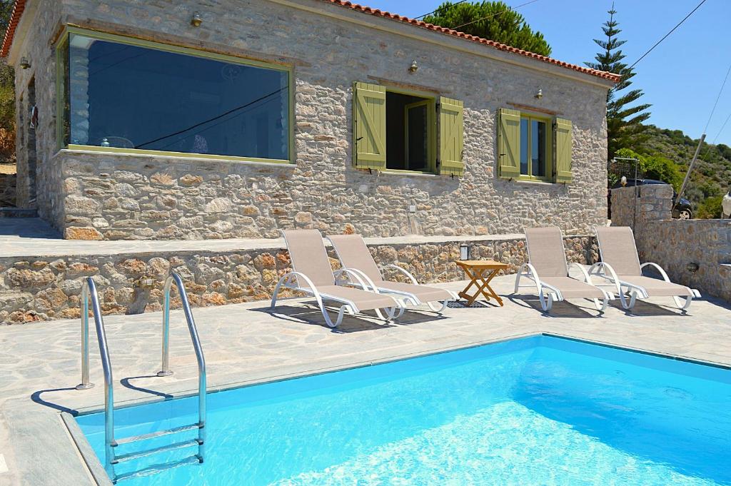 a villa with a swimming pool and chairs and a house at Villa Rokanes Glass Stone with Pool in Kouvéllai