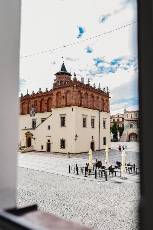 a large brick building with benches in front of it at Apartamenty Rynek 12 in Tarnów