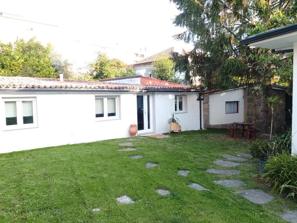 a backyard of a white house with a green yard at Xeitosa II, en el centro de Vigo in Vigo