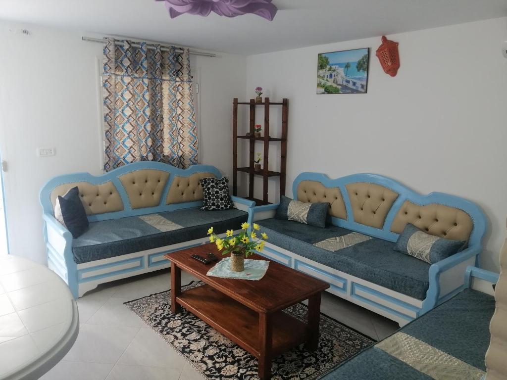 a living room with two blue couches and a table at Studio Yakina in El Haouaria