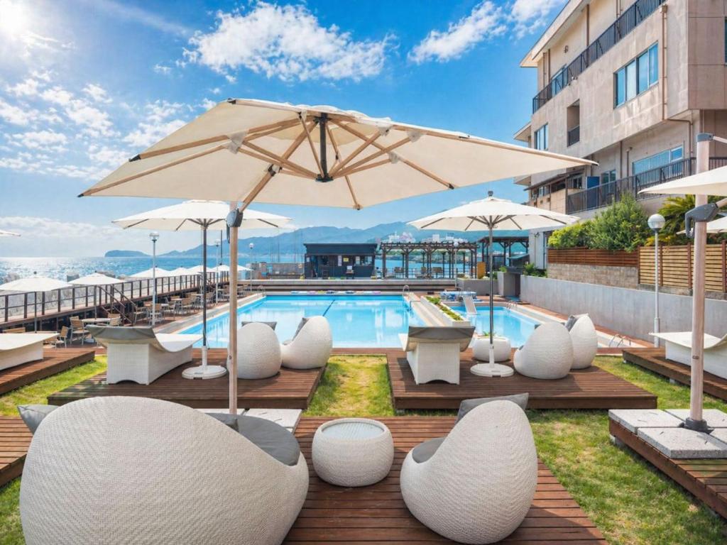 a pool with white chairs and umbrellas at Awakan in Sumoto