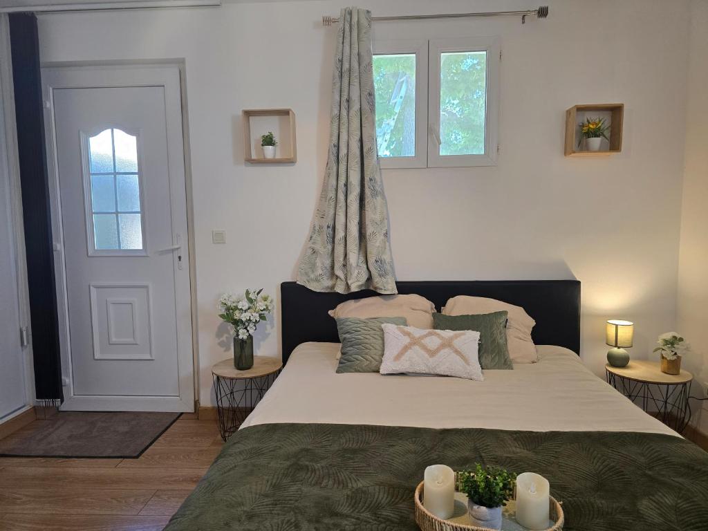 a bedroom with a large bed and two windows at Appartement le Tilleul - Apparts Cosy in Saint-Pons