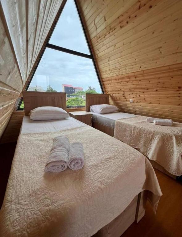 two beds in a room with a large window at Hotel Zhara in Kobuleti