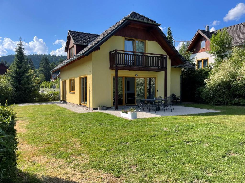 a yellow house with a patio and a yard at LIPNO Hideaway in Kramolín